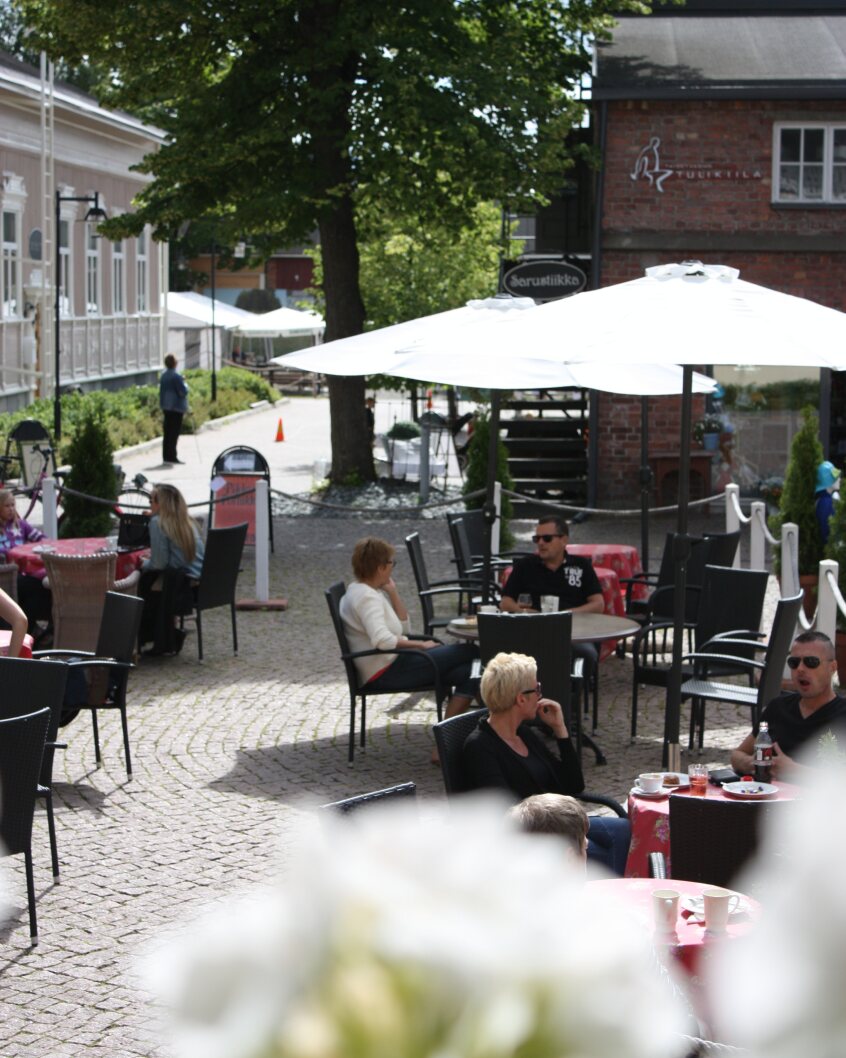 Aurinkovarjoja ja pöytiä Taitokorttelin sisäpihalla